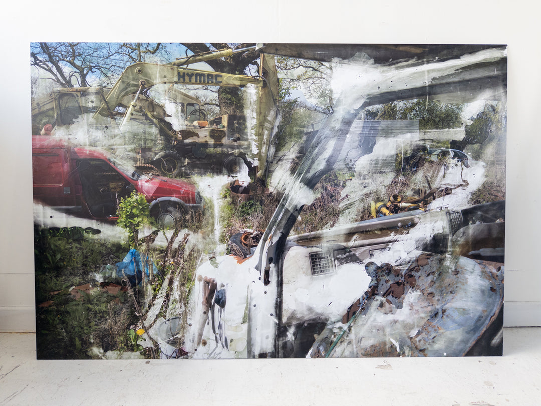 Layered image of a scrapyard scene featuring old vehicles, a red van, a yellow HYMAC digger, overgrown grass, and rusted machinery, with painterly chemical textures and white streaks applied over aluminium.