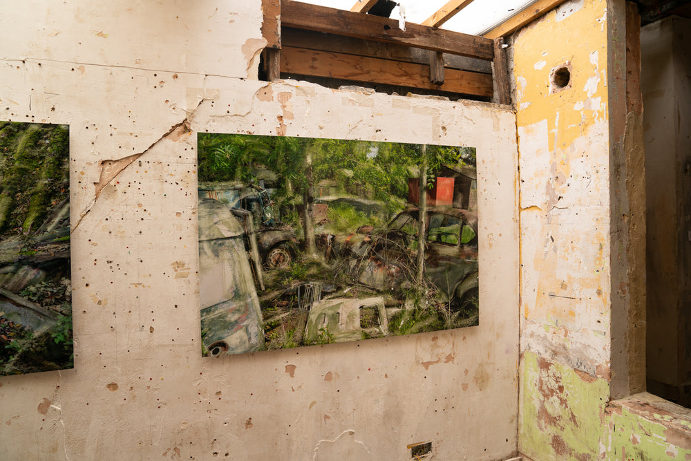 An eerie yet poetic composition of rusted cars and disused vehicle parts overtaken by wild greenery. Trees grow through corroded bonnets and windshields, while a faded red structure peeks through the foliage. Soft overlays and chemical-like textures give the scene a painterly, dreamlike quality—blending dereliction with renewal in a haunting meditation on time and decay.
