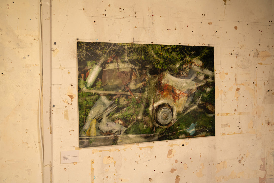 A rich, layered image of industrial remnants and overgrown vegetation, where rust-streaked white vehicle panels, twisted metal, and collapsed timber are partially engulfed by brambles and wild greenery. A circular wheel hub juts from the foreground, surrounded by painterly overlays and textural transparency. The composition speaks to entropy, reclaiming nature, and the slow poetry of decay.