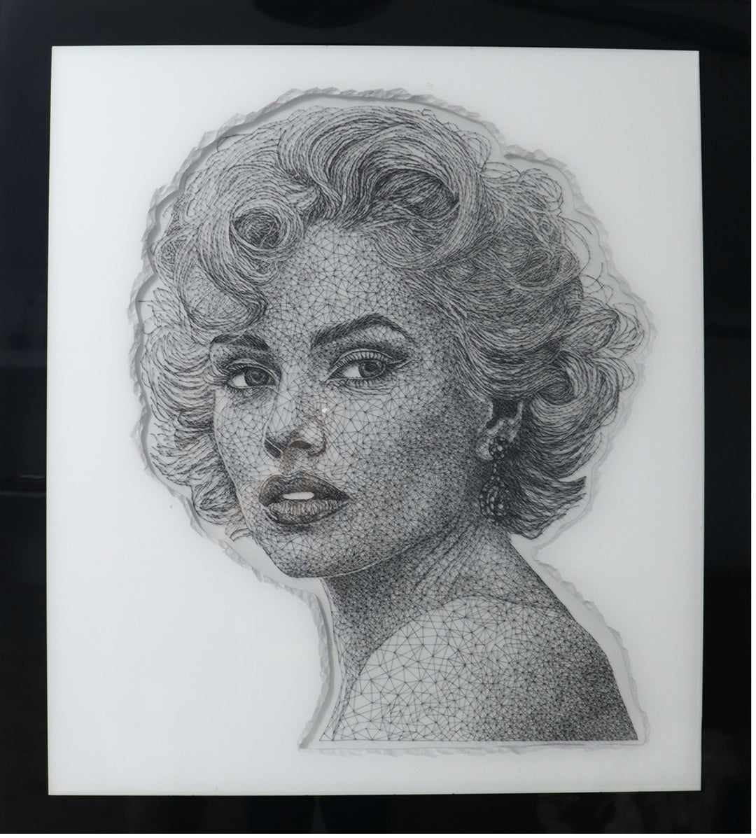 Portrait of a glamorous woman created with intricate black string threaded through thousands of tiny nails, forming detailed facial features and hair on a white panel.