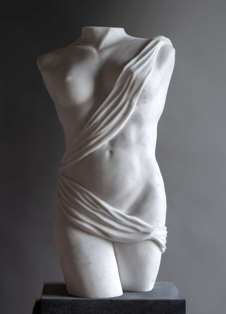 Lucy Unwin marble sculpture Venus, hand carved from white Statuary Carrara marble, depicting a contemporary female torso partially wrapped in flowing carved drapery with smooth figurative contours and finely detailed folds.
