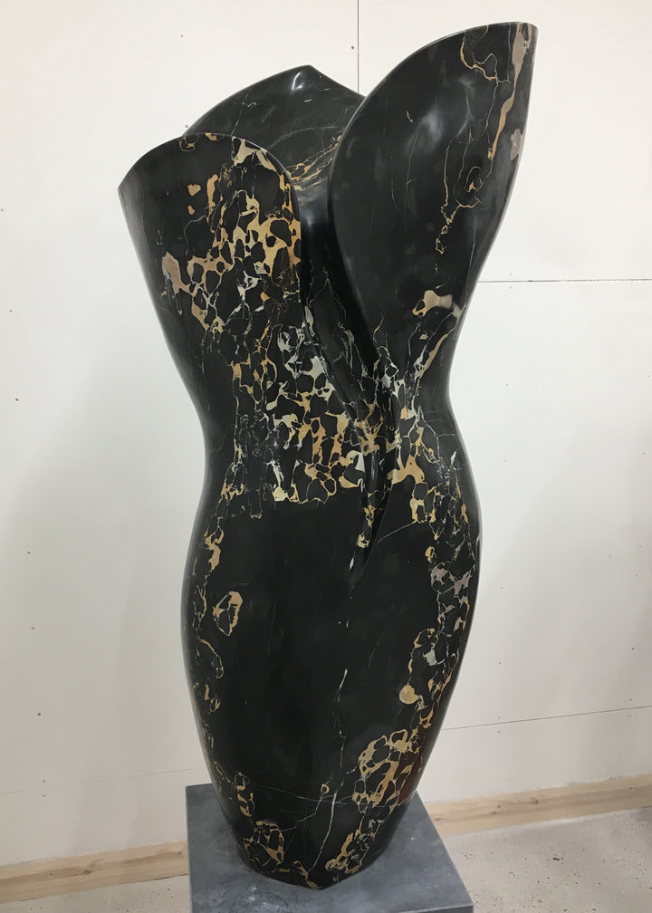 Large contemporary sculpture carved from luxurious Portoro marble, its tall, feminine form flowing with soft curves and dramatic black surface veined with striking gold and ivory patterns, standing on a solid stone plinth.