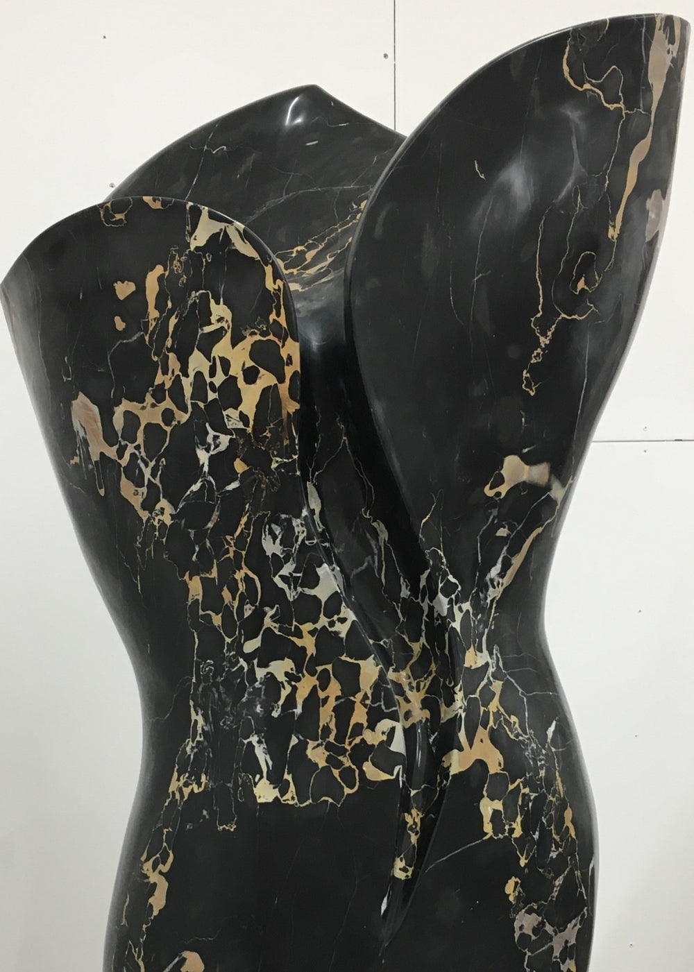 Large contemporary sculpture carved from luxurious Portoro marble, its tall, feminine form flowing with soft curves and dramatic black surface veined with striking gold and ivory patterns, standing on a solid stone plinth.