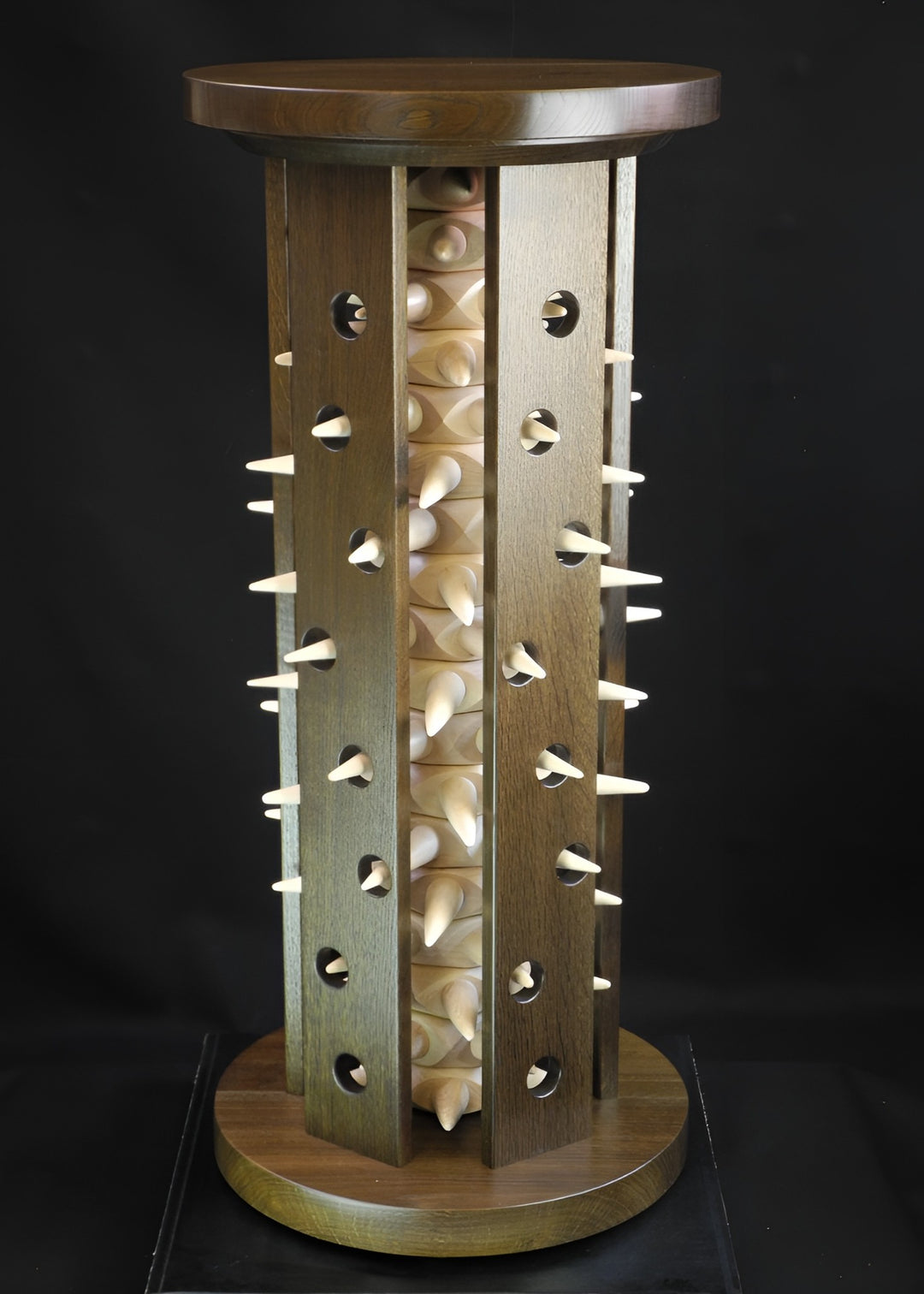 Sculptural Virus Table in fumed oak and maple, a striking cylindrical form with spiked protrusions radiating from pierced panels, blending organic rhythm with architectural precision in a bold technorganic design.