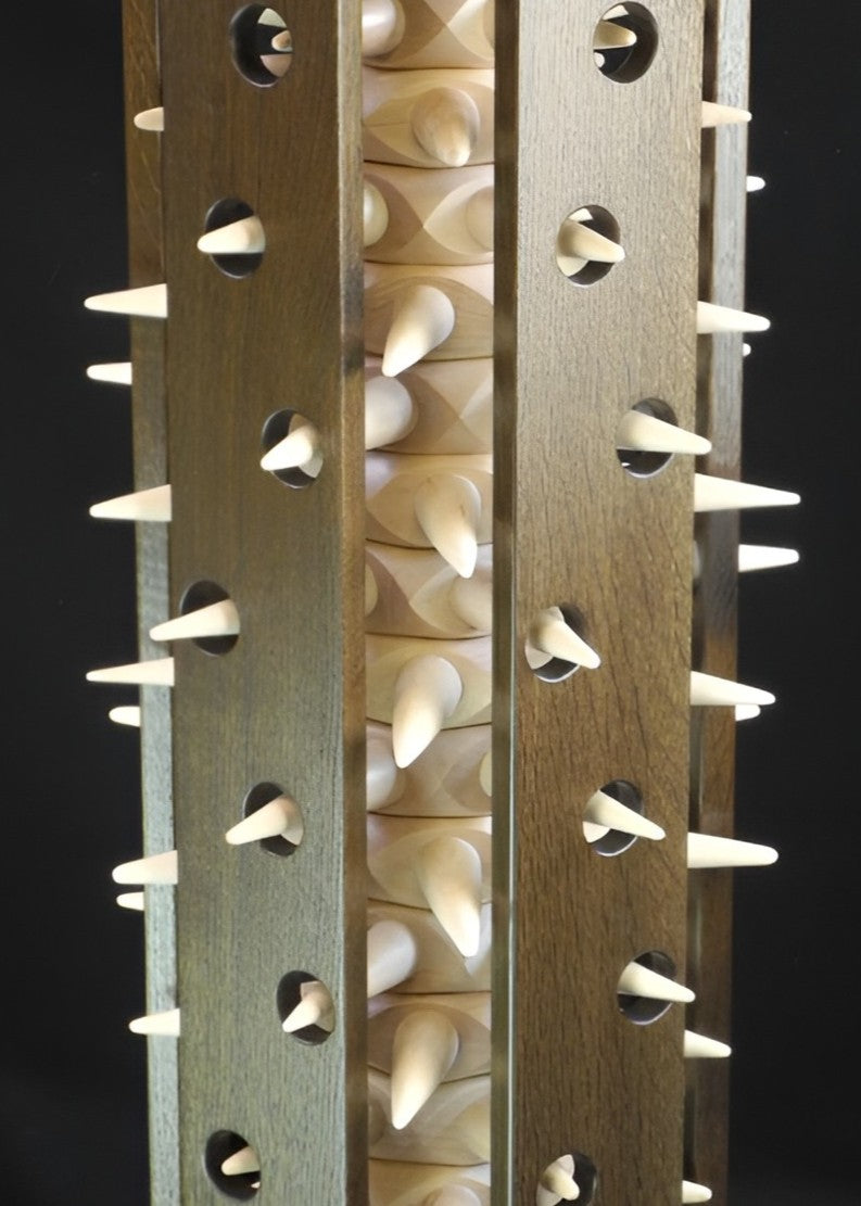 Sculptural Virus Table in fumed oak and maple, a striking cylindrical form with spiked protrusions radiating from pierced panels, blending organic rhythm with architectural precision in a bold technorganic design.