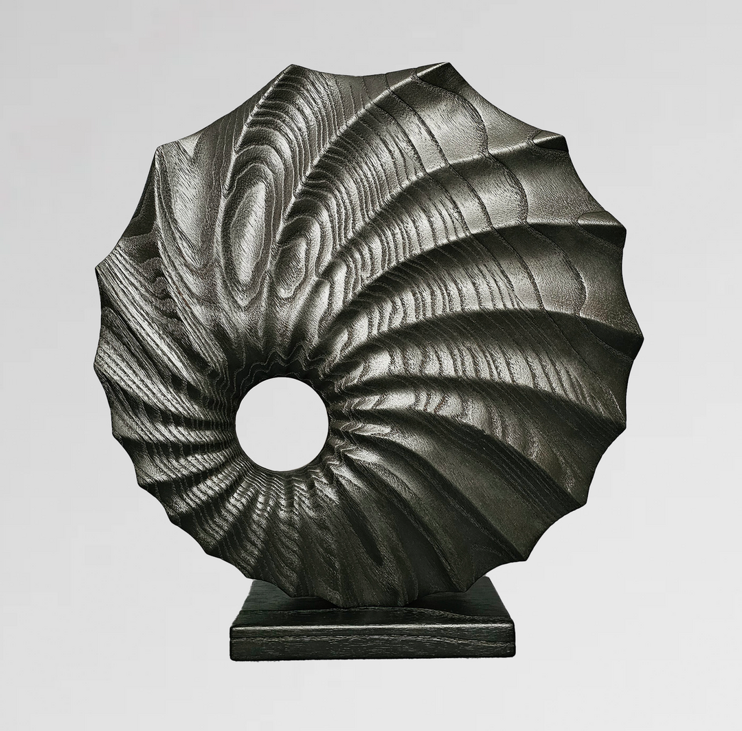 carved wood sculpture in black finish with spiral textures and central circular voids on black base.

