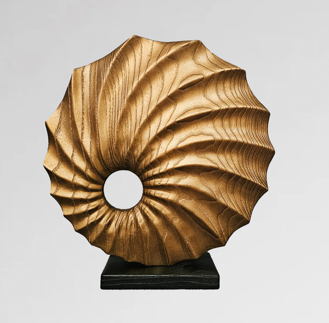 carved wood sculpture in copper finish with spiral textures and central circular voids on black base.
