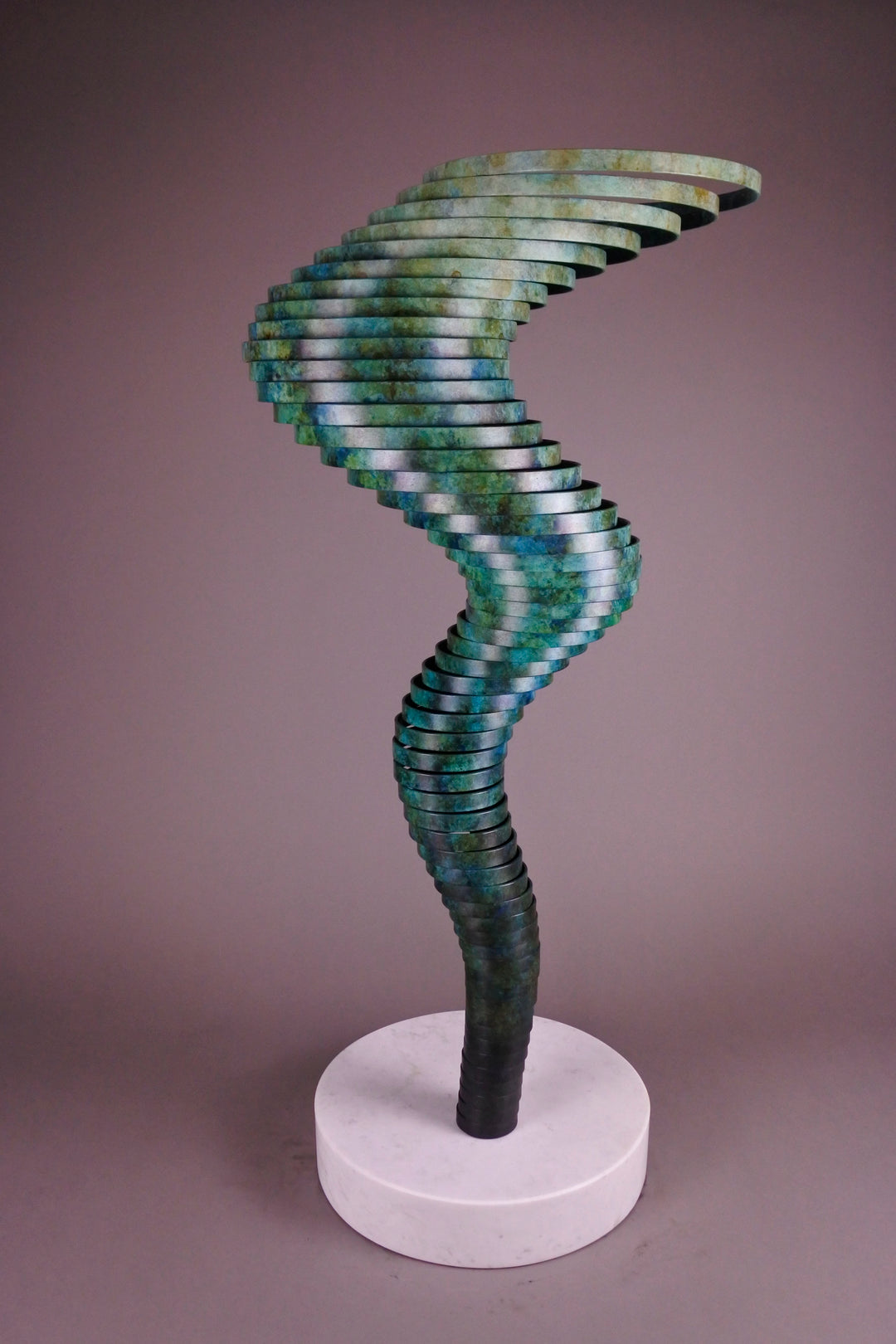 Vortex II by Thomas Joynes – a limited edition bronze sculpture with artisan patina, exploring Fibonacci-based forms through stacked, spiralling discs. The rich verdigris patina in green-blue and rust tones highlights the rhythmic, wave-like movement of the bronze layers. Mounted on a smooth Carrara marble base, the piece brings a sense of elegance and kinetic energy to any contemporary interior.