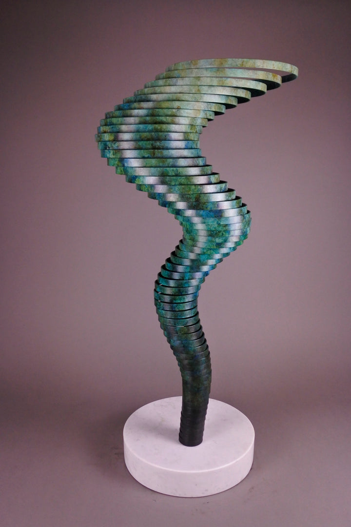 Vortex II by Thomas Joynes – a limited edition bronze sculpture with artisan patina, exploring Fibonacci-based forms through stacked, spiralling discs. The rich verdigris patina in green-blue and rust tones highlights the rhythmic, wave-like movement of the bronze layers. Mounted on a smooth Carrara marble base, the piece brings a sense of elegance and kinetic energy to any contemporary interior.