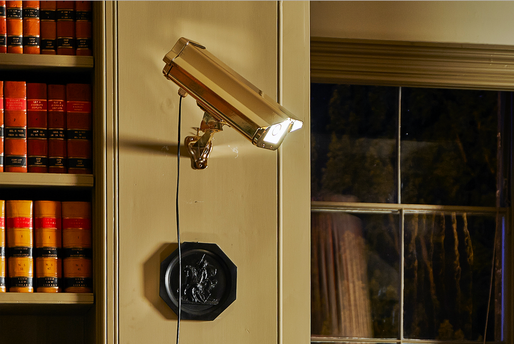 “CCTV Lights – Wall Hung” by Ben Rousseau – a gold-plated light sculpture transforming a surveillance camera into a striking wall-mounted LED artwork. A playful yet luxurious statement merging art, technology, and illumination.

