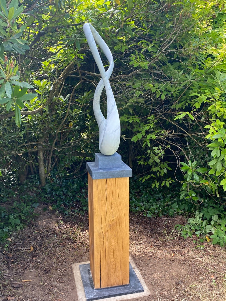 Abstract marble sculpture Wanderer – 2025 by Hamish Holman, hand-carved from Carrara marble into a tall twisting loop form with smooth white veined stone, mounted on a dark stone and oak plinth for display.
