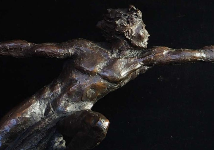 Bronze figurative sculpture by Eve Shepherd showing a dynamic human figure lunging forward with outstretched arms, balanced on a textured base, capturing tension, desire, and suspended movement against a dark background.