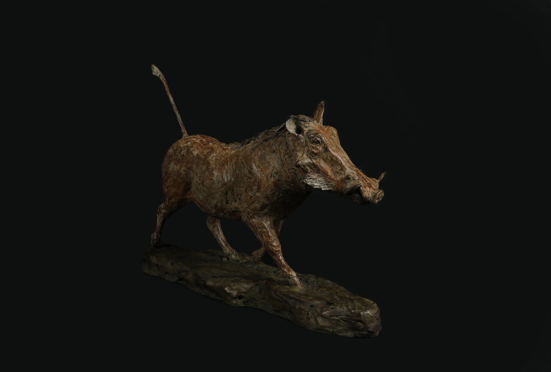 Bronze sculpture of a warthog mid-stride, with textured surface detailing and raised tail, mounted on a naturalistic base