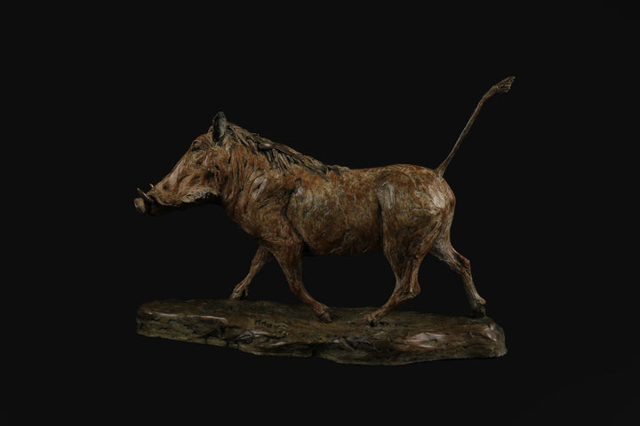 Bronze sculpture of a warthog mid-stride, with textured surface detailing and raised tail, mounted on a naturalistic base