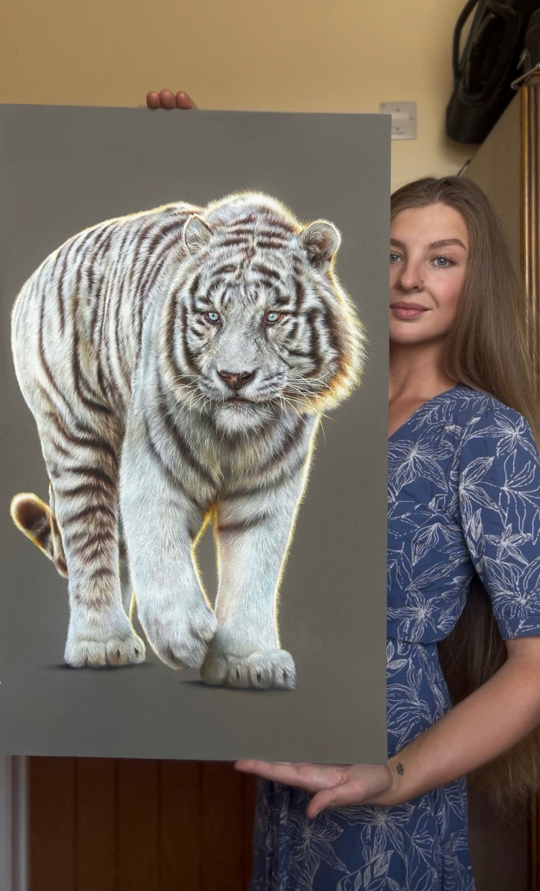 Hyperrealistic coloured pencil drawing of a leucistic Bengal tiger titled Whitewalker, created by Jemma Worsfold. The tiger, named Mohan, is depicted mid-step with striking blue eyes and soft white fur marked by light brown stripes, rendered in exquisite detail on dark grey pastelmat board.