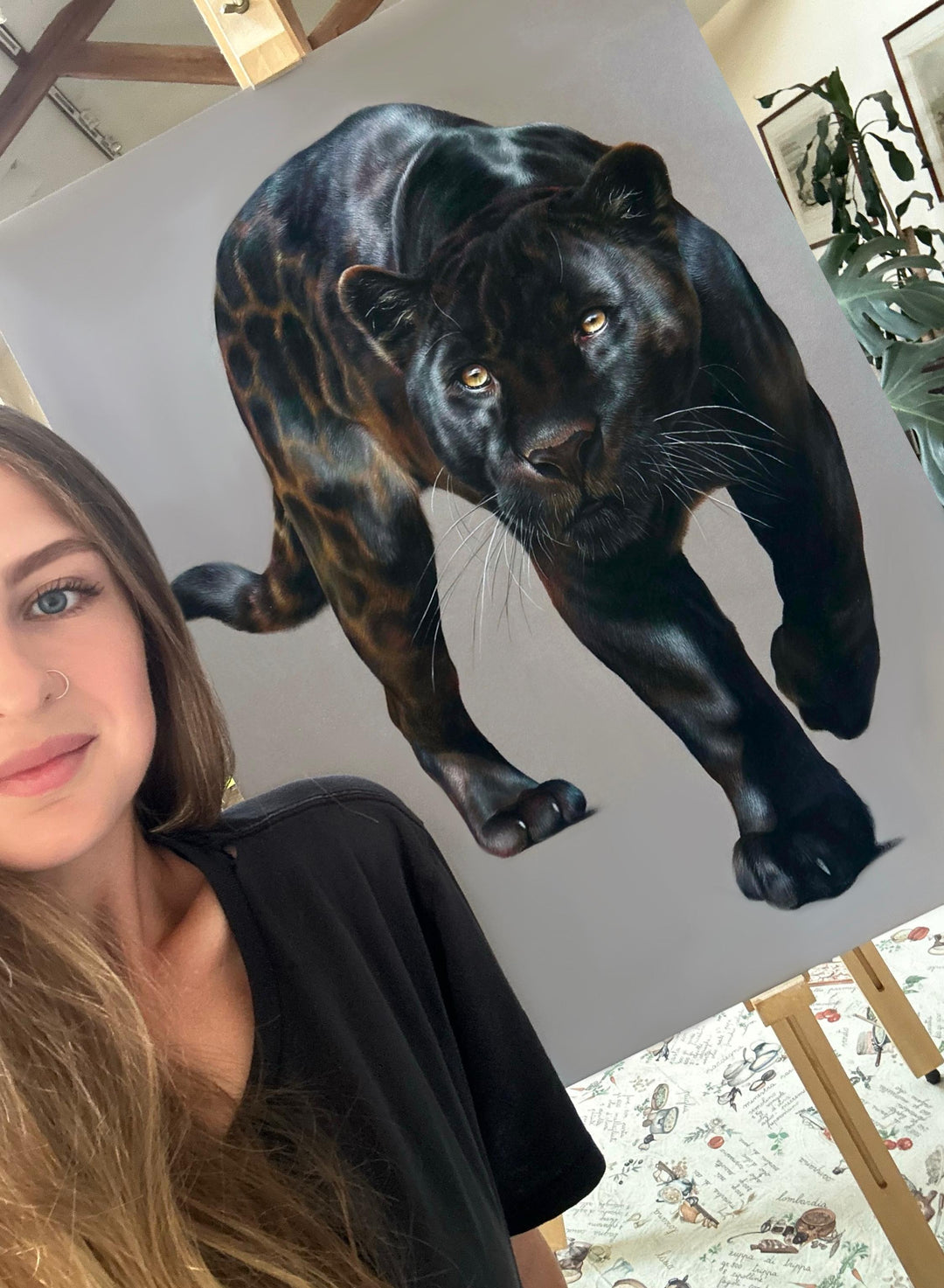 Jemma Worsfold’s Silent Shadow, hyper-real coloured pencil portrait of Neron the melanistic jaguar, golden eyes fixed ahead, sleek black coat with bronze-brown ghost rosettes, on dark grey pastelmat, capturing power, elegance, and predatory grace.