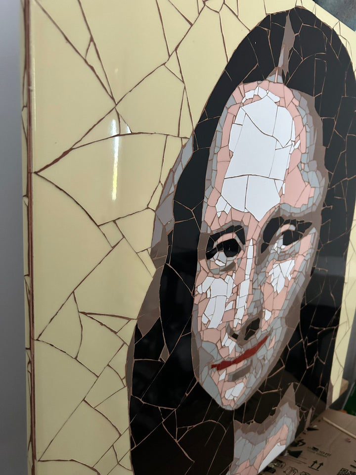 Ed Chapman Mosaic portrait of the Mona Lisa constructed from precisely cut ceramic tiles, with angular fragments forming the face, hair and clothing through subtle tonal shifts, set against a bold yellow background and creating a structured, tactile surface with visible tile joins and rhythmic patterning.
