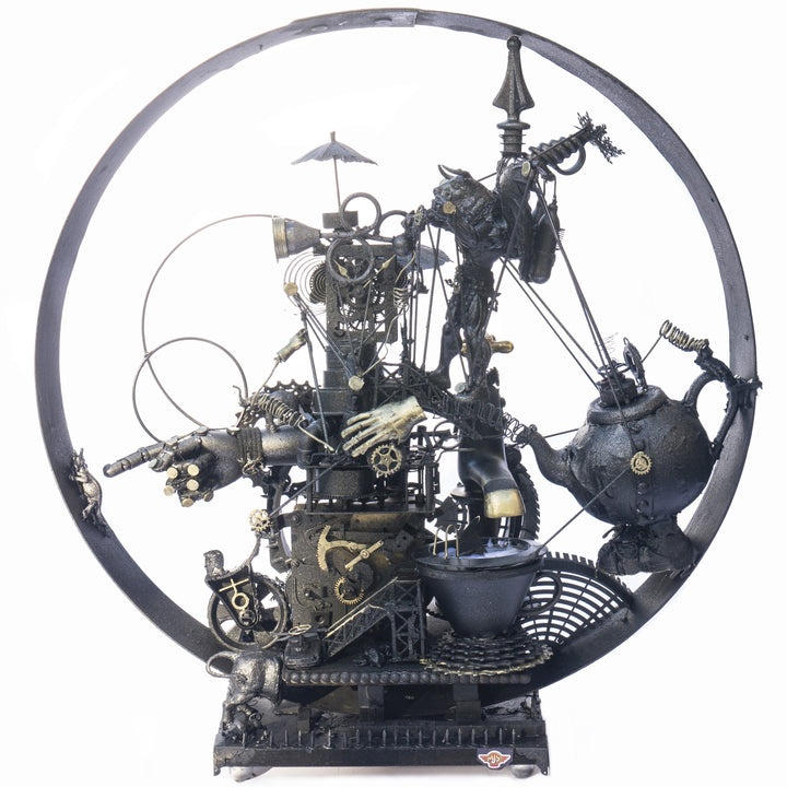 Steampunk assemblage sculpture built from recycled objects including broken toys, china fragments, metal gears, pipes, teapot, figurative limbs and mechanical components, all finished with a dark bronze patina inside a circular frame.