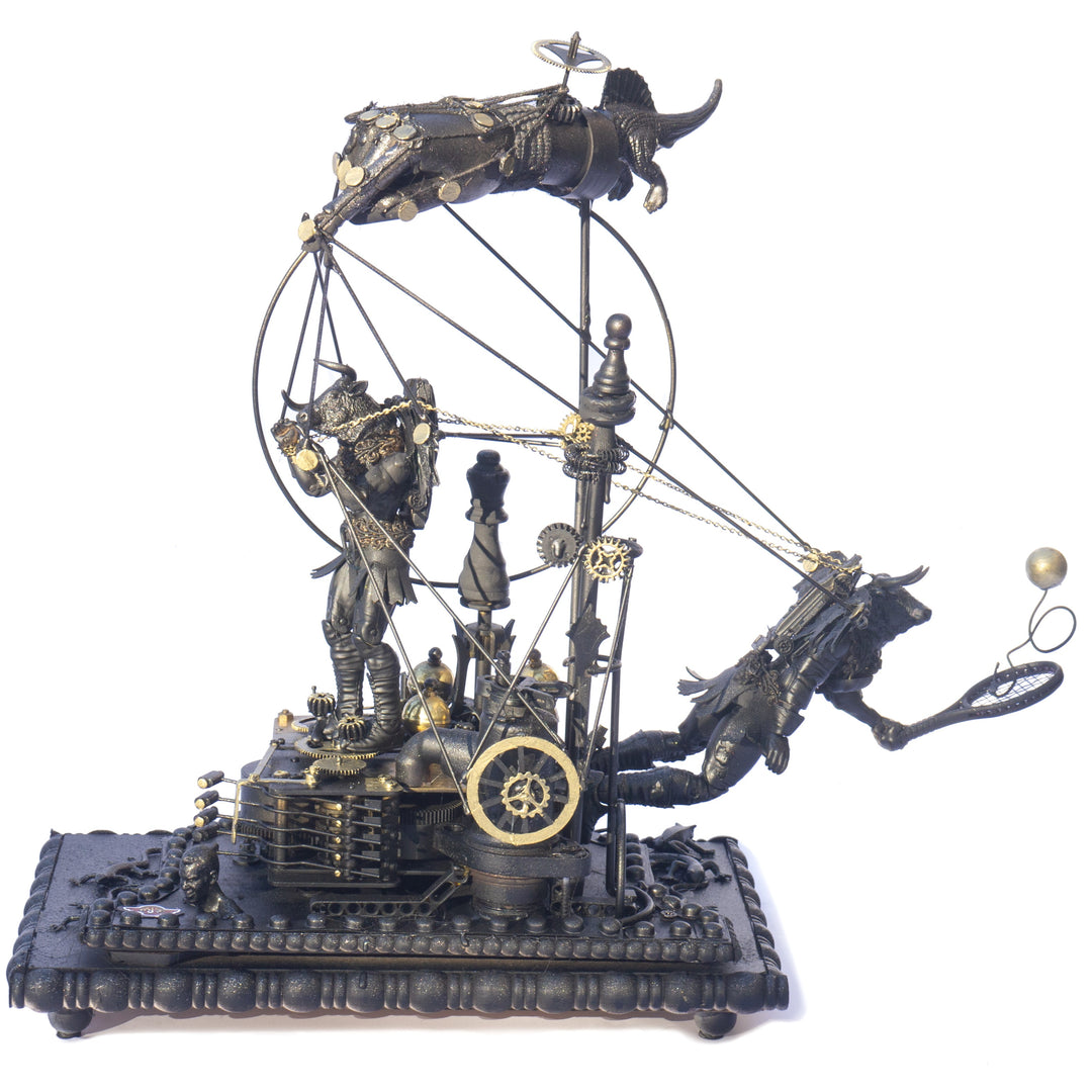 A steampunk sculpture featuring winged minotaur figures assembled from broken toys, brass clock parts, wood offcuts and metal components, all finished in a dark bronze patina. The figures appear in playful motion, including one holding a tennis racket, set on an ornate mechanical base with gears and cogs.