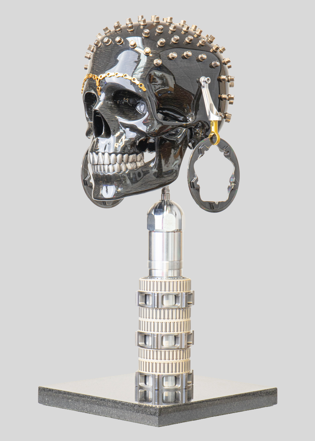 Alastair Gibson CarbonArt45 carbon fibre skull sculpture with high-gloss finish, Formula One components, stainless steel bolt crown detail, gold-plated accents and precision-engineered metal base