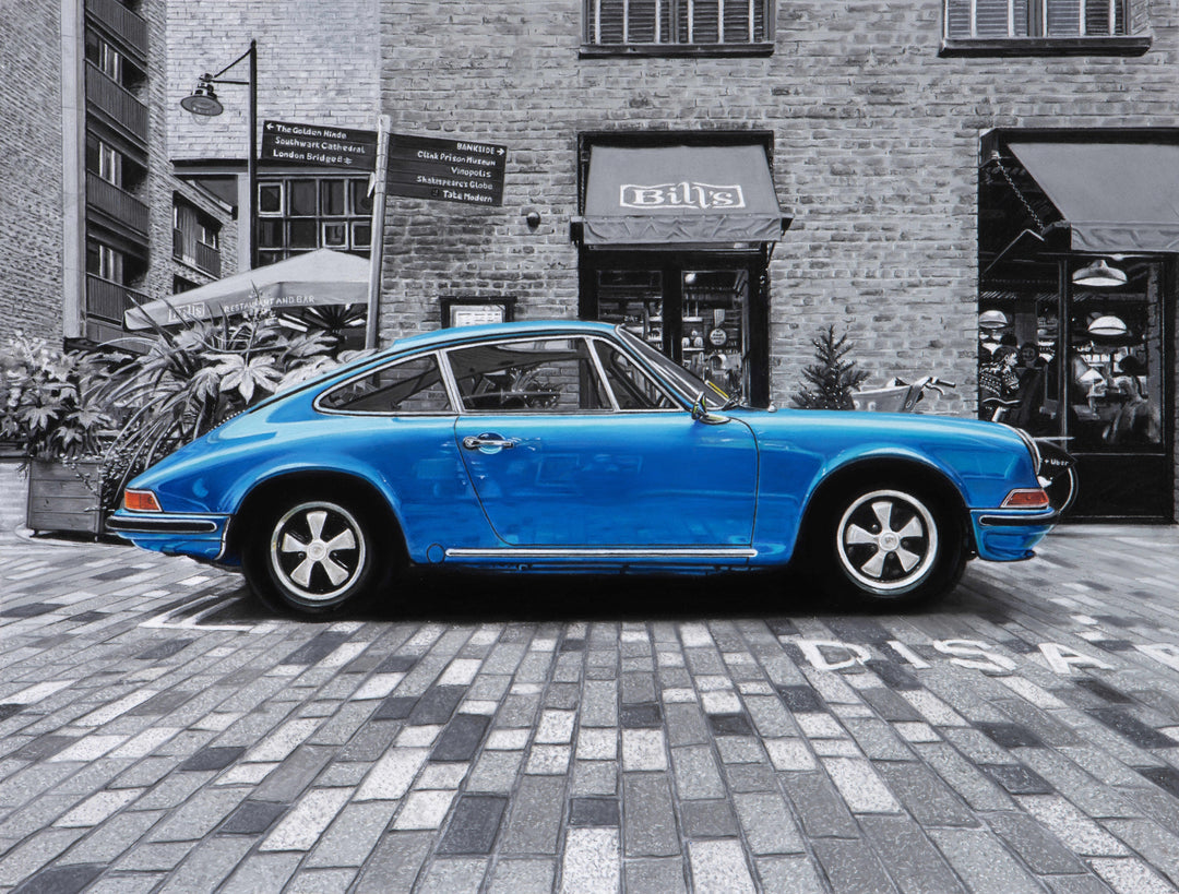 Limited edition giclée print by Ray West depicting a blue 1971 Porsche 911 parked on London’s Southbank, rendered in hyper-realistic pastel detail with the car set against a finely detailed monochrome urban backdrop, printed on archival quality fine art paper.