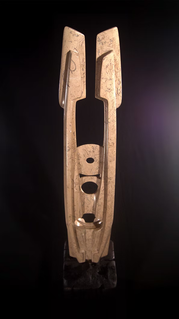 A tall abstract stone sculpture with two inward-facing vertical spires joined at the base, carved in contrasting smooth and textured Purbeck stone, mounted on a dark granite base.