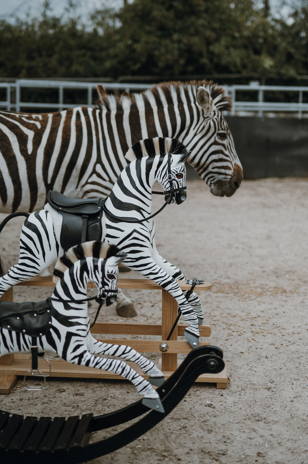 Hand-painted wooden rocking zebra with black leather saddle, mounted on a dark oak safety stand.
