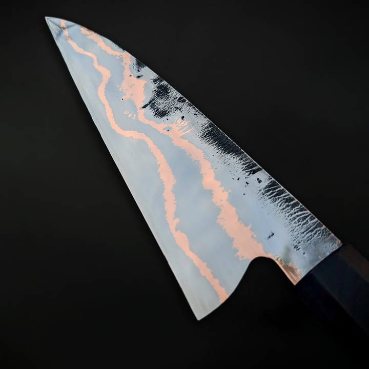 210mm handcrafted chef knife by Beggs Forgeworks, forged from Ardnamurchan whisky cask steel bands and copper-clad Sheffcut carbon steel, with a handle made from original oak staves and a blackwood ferrule—celebrating craftsmanship, heritage, and culinary ritual.