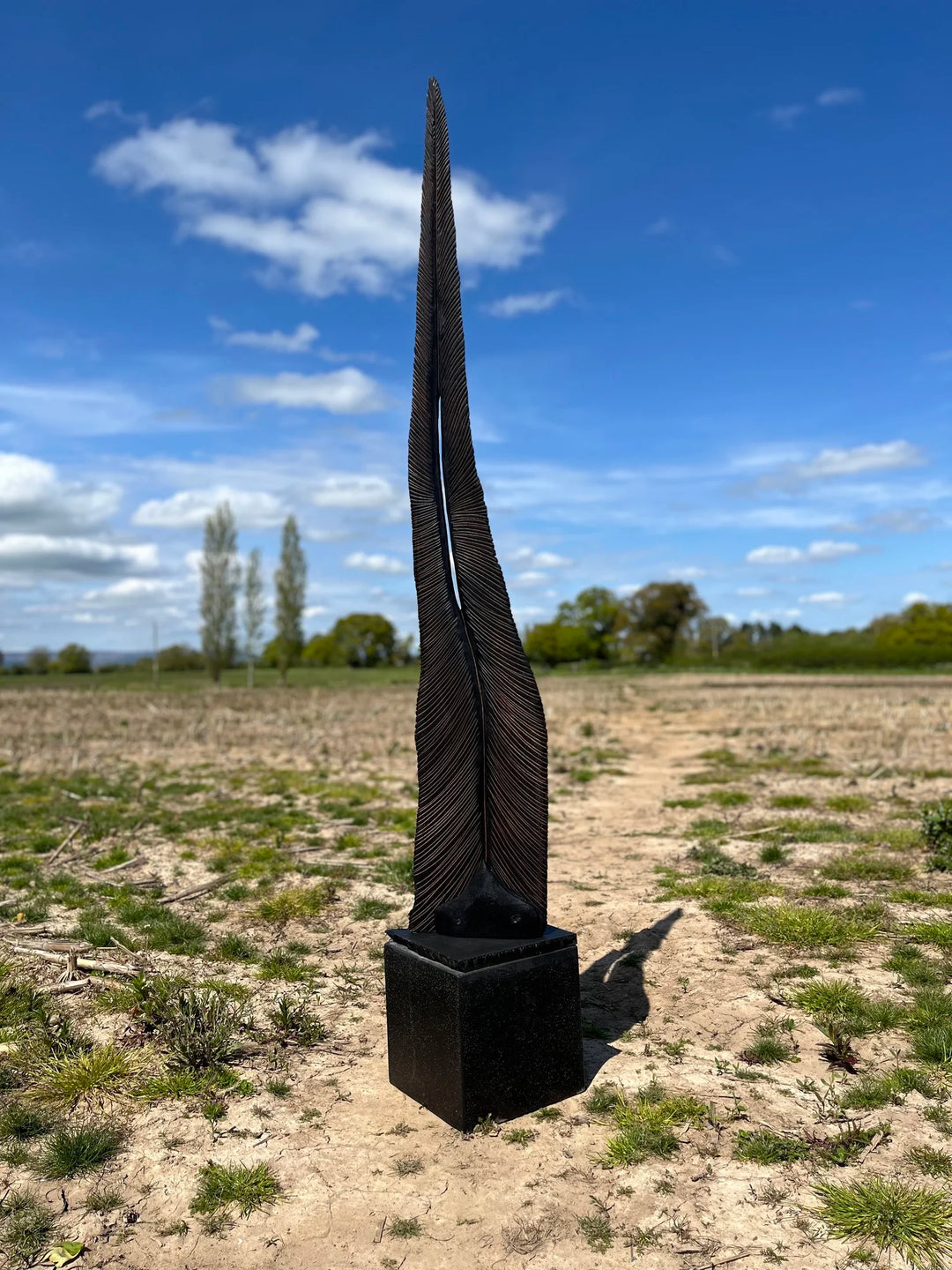 Tall oak sculpture by Glen Farrelly titled Beltane, carved with fine rhythmic grooves and finished using the Yakisugi technique. Charred blackened wood with bronze undertones, symbolising spring, fertility, and renewal.