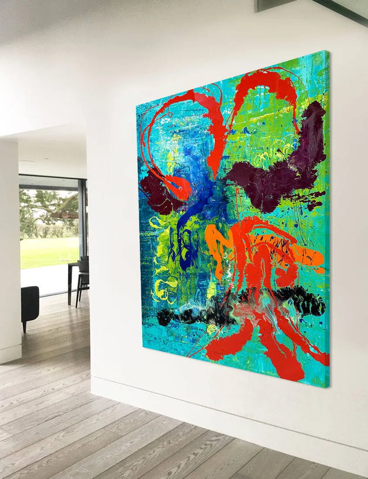 Large abstract painting “Infinite Light” by Swarez — vibrant sweeping strokes of scarlet red, fiery orange and deep burgundy layered over a luminous turquoise and lime green base, with accents of cobalt blue and black. Highly textured enamel surface with bold movement and glossy, light-catching details.