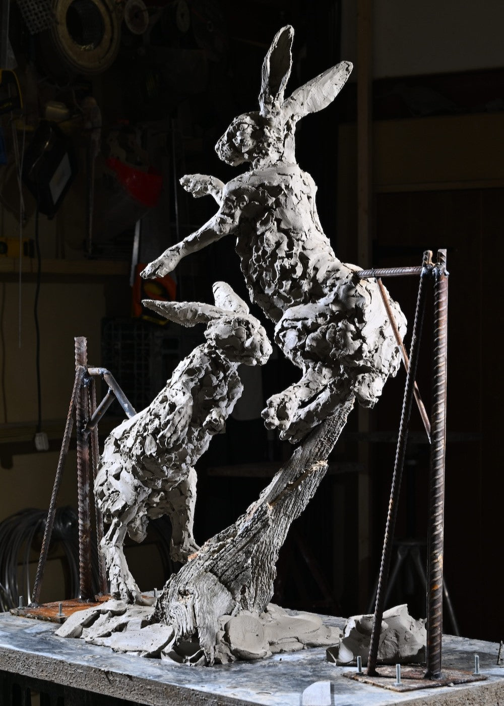 ‘Boxing Hares’ by Hamish Mackie, a limited-edition bronze wildlife sculpture depicting two hares leaping and boxing in mid-air during their characteristic springtime courtship behaviour. The dynamic composition captures their extended limbs, twisting bodies and expressive movement, with richly textured surfaces that convey the energy of the original hand-modelled clay. Photograph shows the original clay sculpture prior to bronze casting.