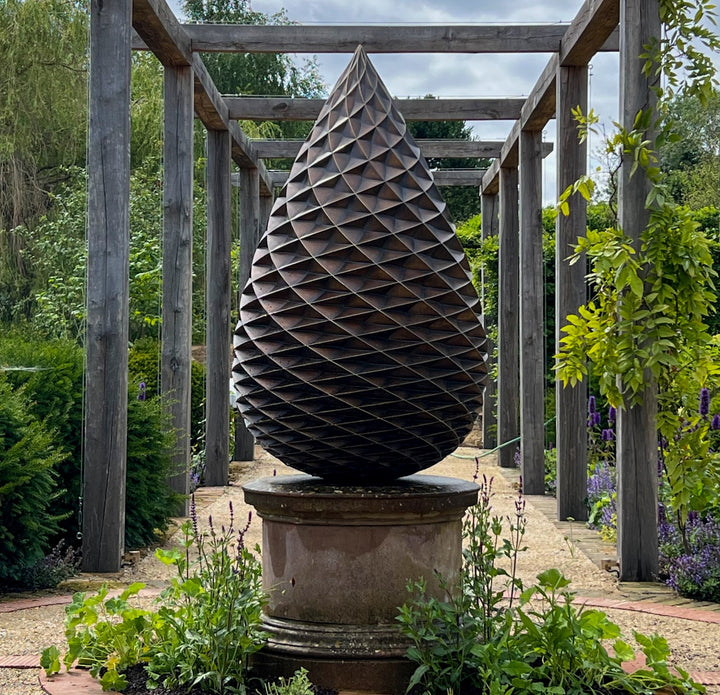 Patinated bronze Pine Cone sculpture by James Parker, with an interlocking spiral surface, geometric scale pattern and tapered organic form inspired by nature and Fibonacci structure.