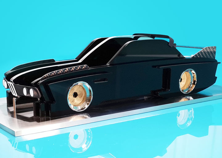 Sculptural model of the 1970s BMW E9 “Batmobile” touring car by Jonny Ambrose — a black, layered acrylic and carbon fibre form with polished aluminium details on a brushed acrylic plinth, capturing its dramatic wings and flared racing silhouette.