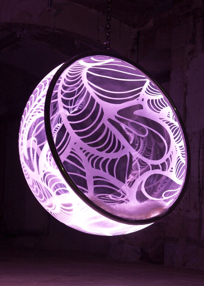 Ben Rousseau, Illuminated Bubble Chair – a limited-edition hanging sphere with engraved acrylic, vibrant pink-purple LED glow, and Mongolian sheepskin cushion featuring INSA’s signature pattern. A cocoon-like statement chair blending art, comfort, and sensory light.