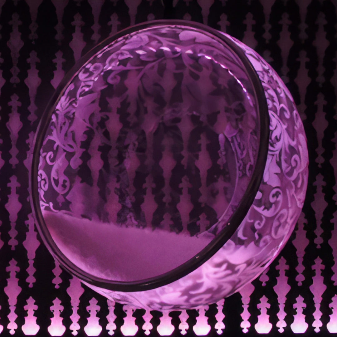 “Illuminated Bubble Chair – Flock Pattern” by Ben Rousseau – a glowing hanging chair crafted from stainless steel, engraved acrylic, and RGB LED light. The spherical design emits soft pink and violet tones, lined with a Mongolian sheepskin cushion.

