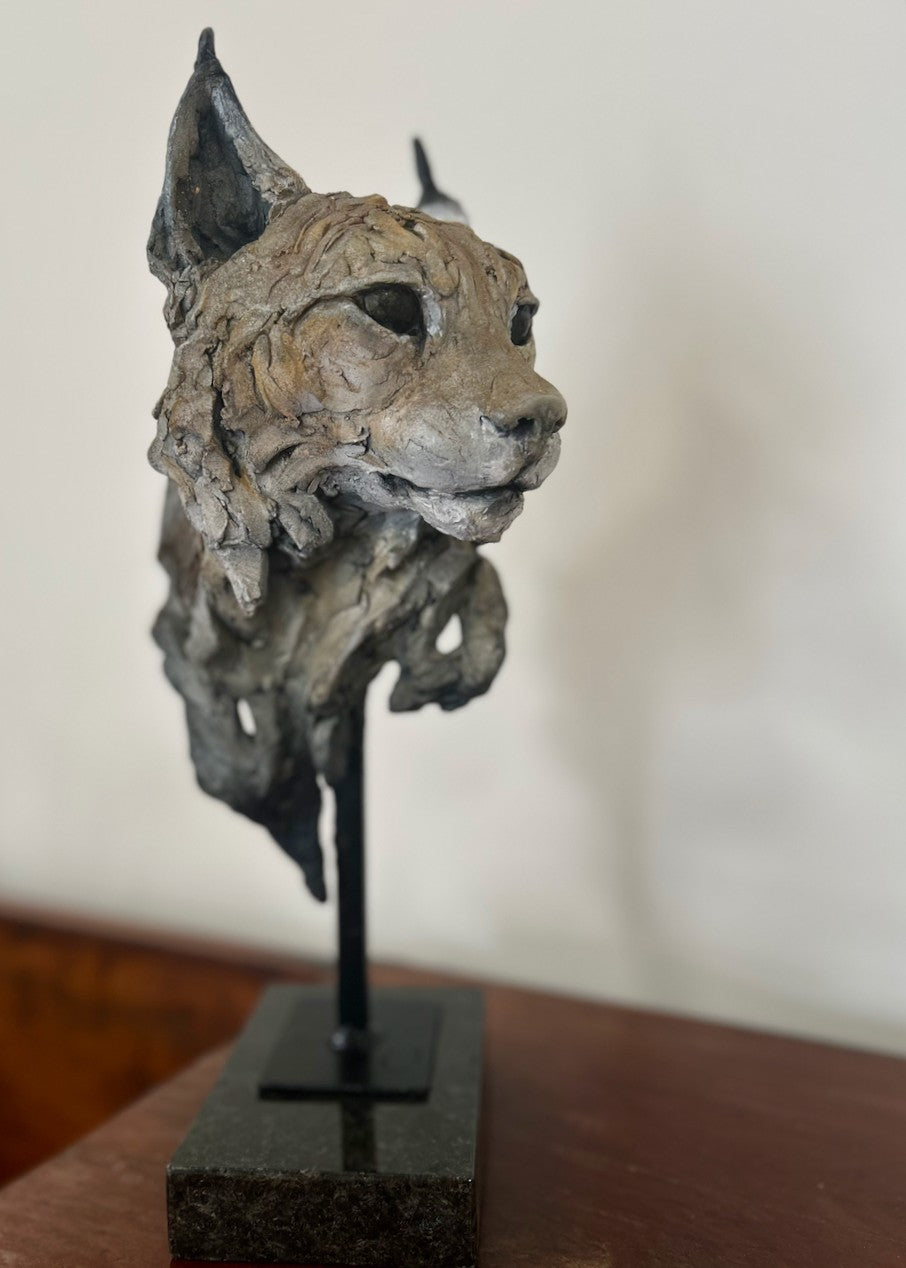 Sculpture of a Eurasian lynx head by Lucy d’Auvergne, cast in slate with raw earth pigments creating warm taupe and grey tones with subtle brown highlights, mounted on a polished granite base.