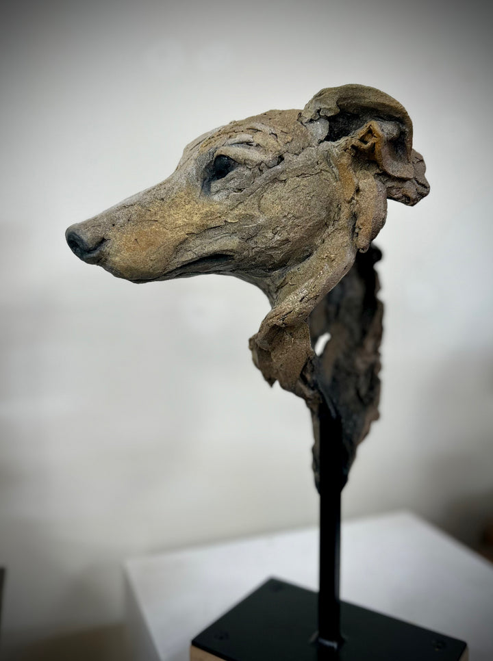 Sculpture of a graceful greyhound head by Lucy d’Auvergne, crafted from cast slate with layered raw earth pigments in warm taupe, grey and ochre tones, mounted on a polished granite base.