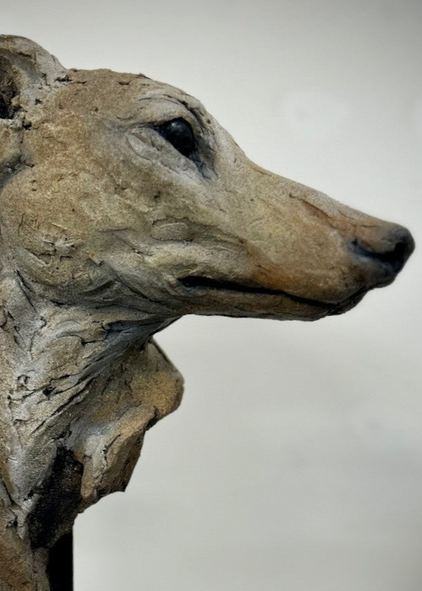 Sculpture of a graceful greyhound head by Lucy d’Auvergne, crafted from cast slate with layered raw earth pigments in warm taupe, grey and ochre tones, mounted on a polished granite base.