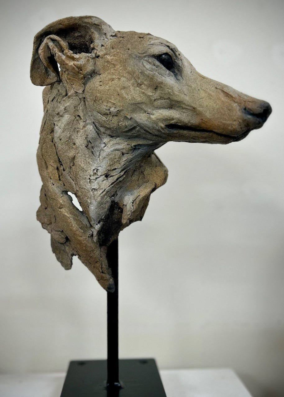 Sculpture of a graceful greyhound head by Lucy d’Auvergne, crafted from cast slate with layered raw earth pigments in warm taupe, grey and ochre tones, mounted on a polished granite base.