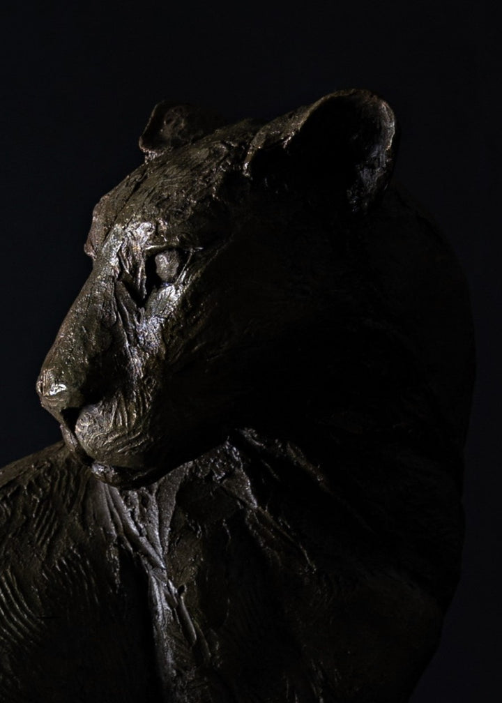 Sculpted panther by Lucy d’Auvergne in dark cold cast bronze with a sleek, muscular form and subtle textured surface, poised on a solid oak plinth against a deep shadowed background.