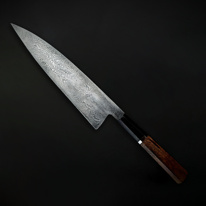 Close-up and full view of a handmade Damascus steel chef’s knife by Beggs Forgeworks, showcasing the intricate layered grain of the forged blade. The unique patterning of the steel, created through repeated folding and etching, is paired with a dark, faceted wooden handle—highlighting the craftsmanship and balance of the blade against a matte black background.