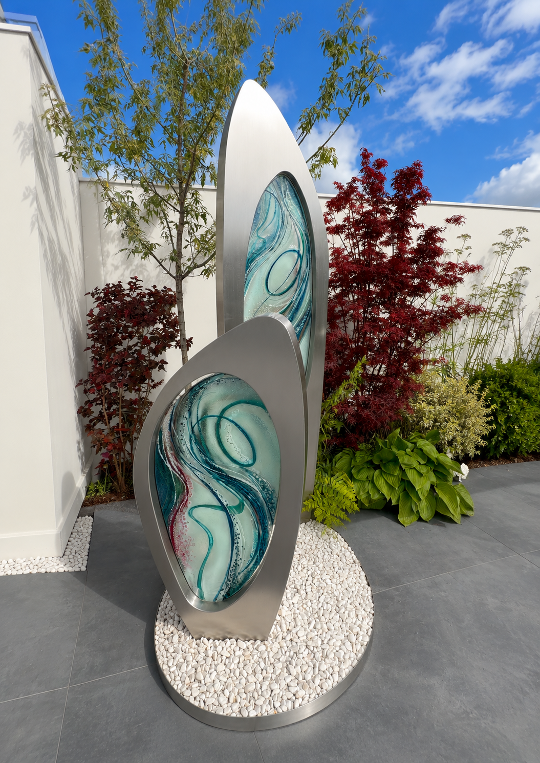 Double Apogee by Carrie-Anne Funnell, a large contemporary outdoor sculpture comprising two sweeping brushed stainless-steel forms inset with layered turquoise, blue and green kiln-formed glass.