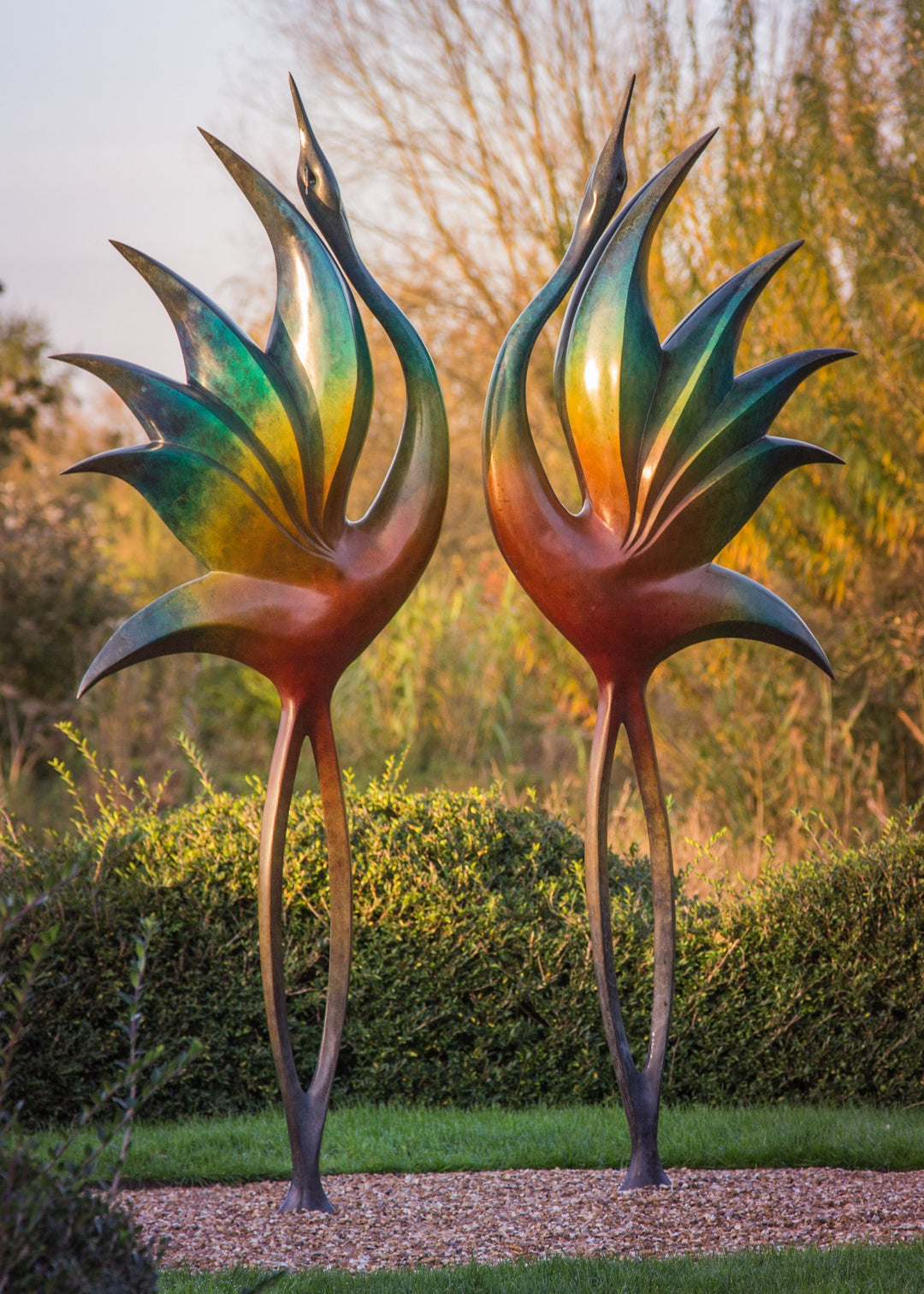Simon Gudgeon bronze sculpture Dancing Cranes featuring elegant crane-inspired organic forms with sweeping upward curves displayed within a landscaped garden setting.