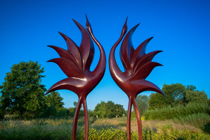 Simon Gudgeon bronze sculpture Dancing Cranes featuring elegant crane-inspired organic forms with sweeping upward curves displayed within a landscaped garden setting.