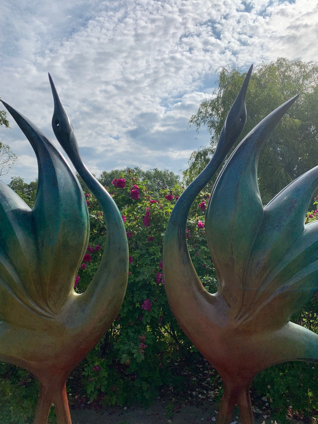 Simon Gudgeon bronze sculpture Dancing Cranes featuring elegant crane-inspired organic forms with sweeping upward curves displayed within a landscaped garden setting.
