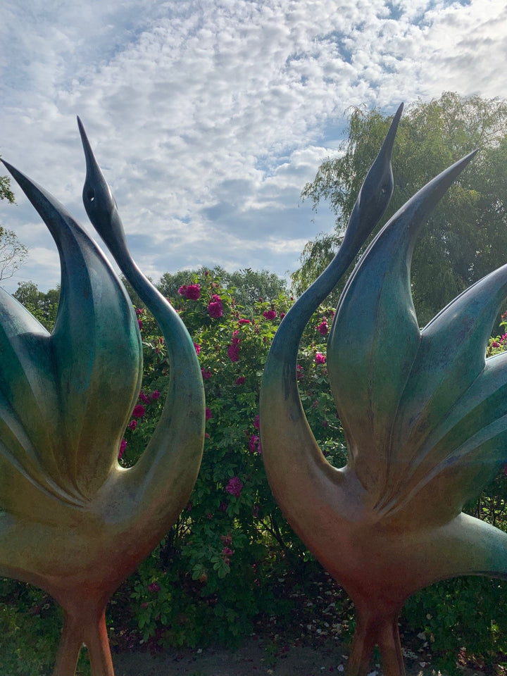 Simon Gudgeon bronze sculpture Dancing Cranes featuring elegant crane-inspired organic forms with sweeping upward curves displayed within a landscaped garden setting.