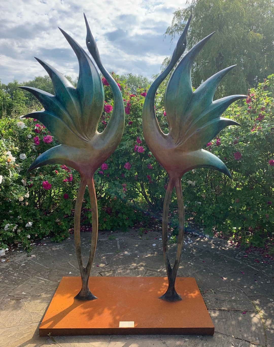 Simon Gudgeon bronze sculpture Dancing Cranes featuring elegant crane-inspired organic forms with sweeping upward curves displayed within a landscaped garden setting.