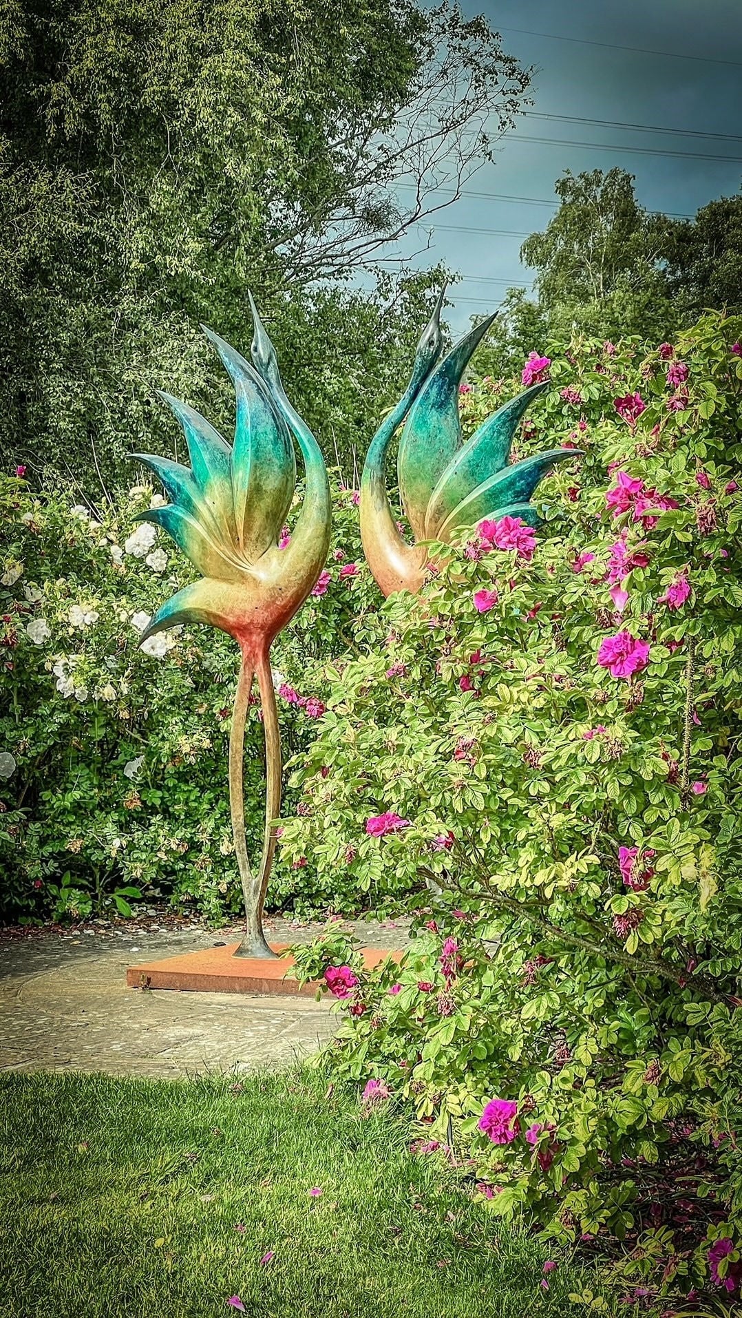 Simon Gudgeon bronze sculpture Dancing Cranes featuring elegant crane-inspired organic forms with sweeping upward curves displayed within a landscaped garden setting.