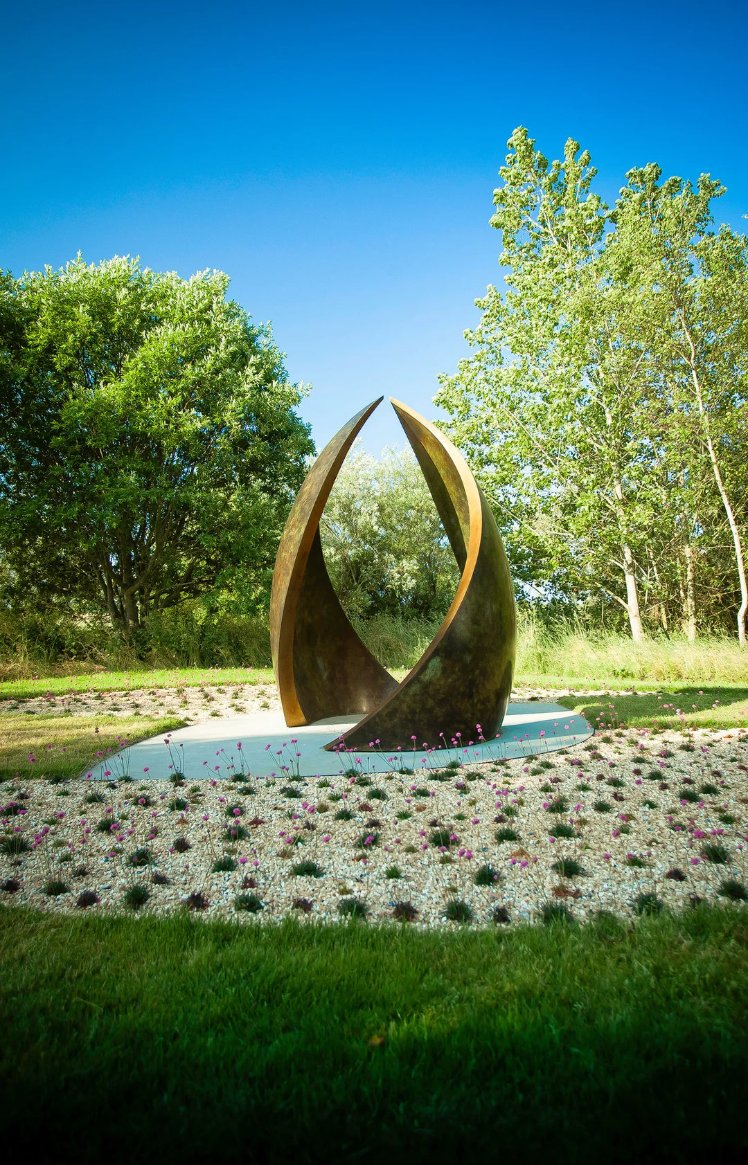 Simon Gudgeon bronze sculpture Embrace featuring monumental abstract curved bronze forms rising upwards and meeting at a central point within a landscaped garden setting.