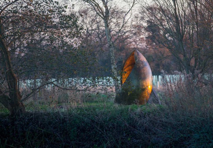 Simon Gudgeon bronze sculpture Embrace featuring monumental abstract curved bronze forms rising upwards and meeting at a central point within a landscaped garden setting.